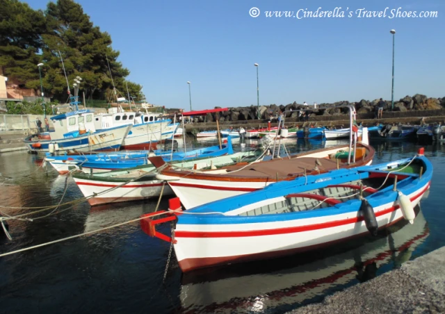 Boats in small harbor next to black sandy beach in Catania